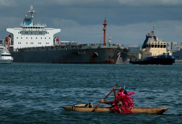 A Pacific Climate Change Warrior paddles into the path of a ship in the worldÃ¢Â€Â™s biggest coal port to bring attention to the impact of climate change on low-lying islands. Courtesy of Dean Sewell/Oculi for 350.org