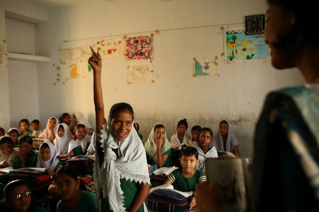 A student at the Hazi Ibrahim Government Primary School in Bangladesh’s capital, Dhaka, raises her hand in response to her teacher’s questions. Credit: Shafiqul Alam Kiron/IPS