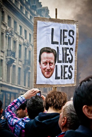 A plaque targeting Prime Minister David Cameron, as demonstrators protest in Oxford Street, London, 26 March 2011.  Credit: Mark Ramsay | Source: http://www.flickr.com/photos/neutronboy/5562337245/ | Creative Commons Attribution 2.0 Generic license.