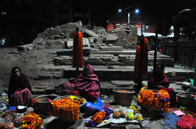 Women sell flowers at dusk in front  of  archaeological  monuments damaged by the April 2015 earthquake in Durbar Square Kathmandu. Credit: Amantha Perera/IPS