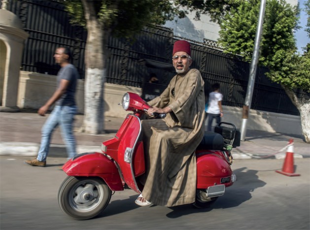 An Egyptian man riding a scooter and wearing a traditional fez known locally as a “tarboush” in Tahrir square Cairo, October 20, 2015.