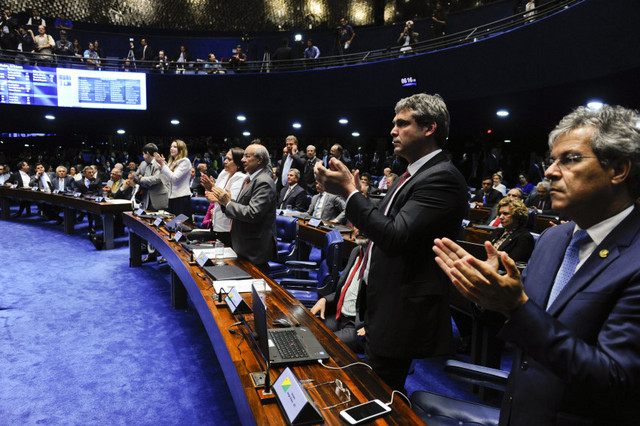 A group of weary senators applaud at the end of the marathon session that decided to immediately suspend President Dilma Rousseff during an impeachment trial for her removal. Credit: Marcos Oliveira/Agência Senado
