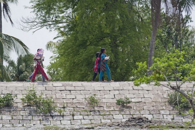 Girls walk across an embankment in the Satkhira district of Bangladesh. The height of the polders needs to be increased to save coastal populations from storm surges and cyclones. Credit: Rafiqul Islam/IPS 