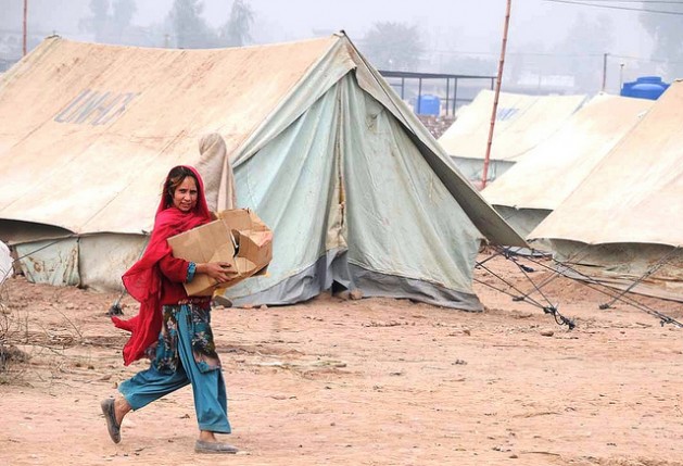 A child carries a box of relief supplies to her tent at the Mardan refugee camp in Pakistan. Credit: Ashfaq Yusufzai/IPS