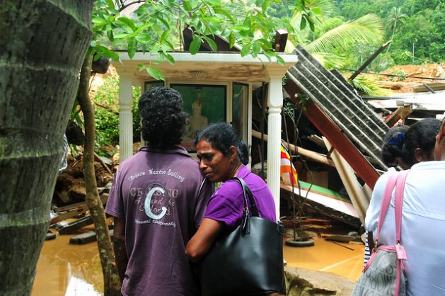 Family members wait near a house buried by the landslide as rescue workers look for survivors. Credit: Amantha Perera/IPS