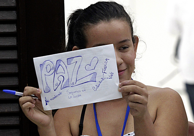 Erika Paola Jaimes, a survivor of Colombia’s armed conflict, holds a sign about peace during a trip to Havana to participate in the peace talks between the government and the FARC rebels, which led to a peace deal signed Jun. 23 in the Cuban capital. Credit: Jorge Luis Baños/IPS
