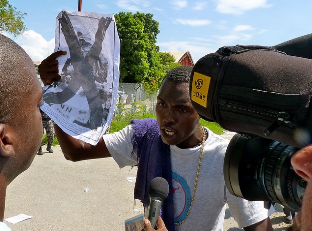 A demonstrator holds up an anti-U.N. poster during a protest outside a UN base in Port-au-Prince, Haiti. Credit: Ansel Herz/IPS