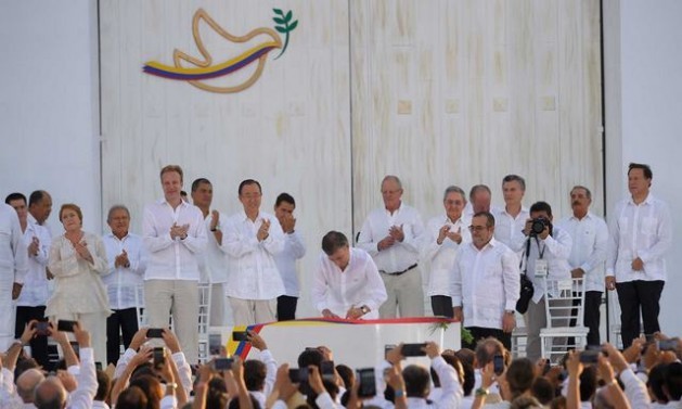 Colombian President Juan Manuel Santos signs the peace agreement, observed by FARC chief Rodrigo Londoño, Latin American presidents and other dignitaries, in an open-air ceremony in the city of Cartagena de Indias. Credit: Colombian presidency