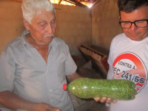 Raimundo Pinheiro de Melo, better known as Mundinho, a 76-year-old farmer who lives in the Apodi municipality in Northeast Brazil, shows a visiting farmer a bottle of bean seeds which he stores and protects. Credit: Mario Osava/IPS