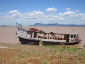 A boat under repair on the shore of the Sobradinho reservoir, which has a low water level due to the five years of drought which has plagued the semi arid interior of Northeastern Brazil. Bushes submerged by the dammed-up waters of the São Francisco river since the 1970s can be glimpsed. Credit: Mario Osava/IPS