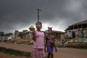 Infrastructure across Liberia, including electricity installations, was destroyed during the country's protracted civil war (1989-2003). Above, girls in the town of Totota in Bong County walk past homes that are being demolished as the government rebuilds roadways. Photo: UN Women