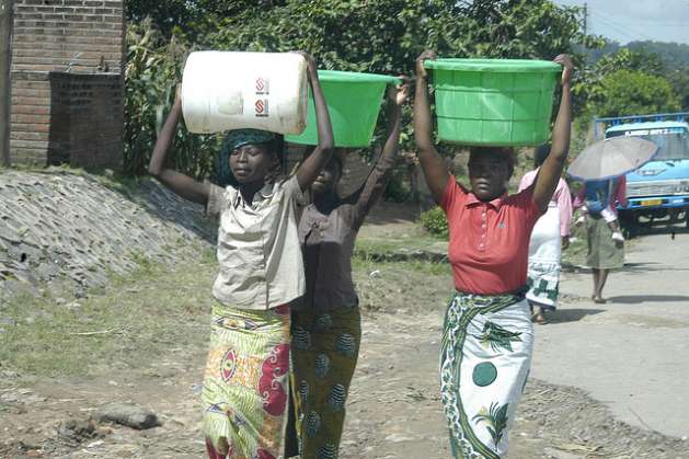 Women return from fetching water after the water in their homes was cut off during the water rationing. Credit: Charles Mpaka/IPS