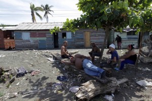 Local residents of La Playa rest under the shade of a bush on a polluted sandbar or “tibaracón” at the mouth of the Macaguaní River, near the city of Baracoa in eastern Cuba. Credit: Jorge Luis Baños/IPS