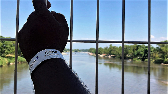 The arm of a migrant, looking from a bridge over the waters of the Suchiate River, the natural border between Guatemala and Mexico, in the southern city of Tapachula, after obtaining the paper bracelet from the National Institute of Migration which will allow him to stay and work in Mexico for at least a year, as part of the government's new reception programme, which began on Jan. 17. Credit: Ángeles Mariscal/IPS