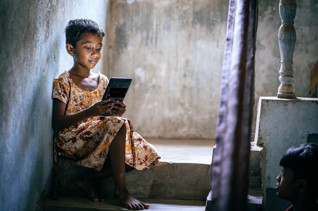 A girl in Bhubaneswar slums, India checks her e-learning assignments on a computer tablet. Courtesy: John Marshall/Aveti Learning